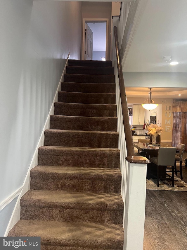 staircase featuring baseboards and wood finished floors