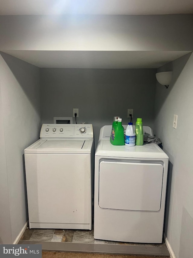 clothes washing area featuring laundry area, separate washer and dryer, and baseboards