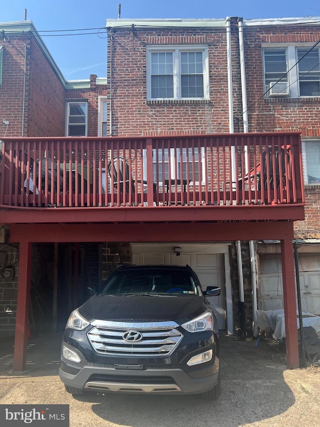 rear view of house with a carport, an attached garage, and brick siding