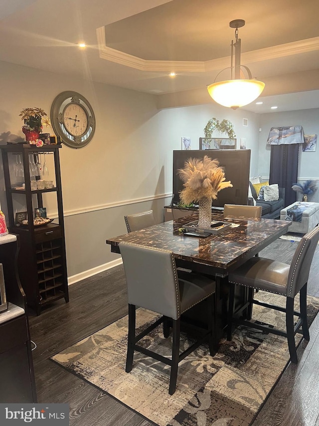 dining area featuring baseboards, dark wood finished floors, a tray ceiling, recessed lighting, and ornamental molding