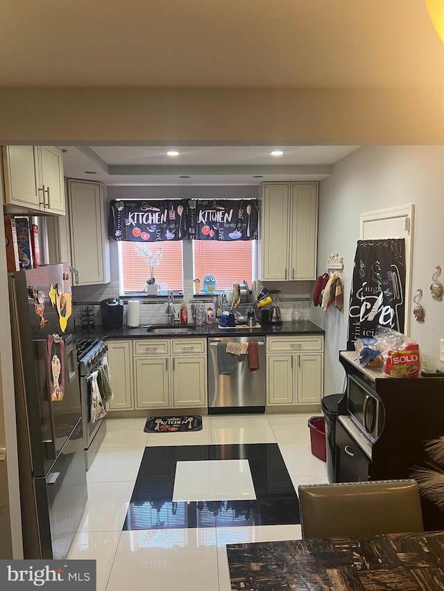 kitchen featuring a sink, dark countertops, appliances with stainless steel finishes, and light tile patterned flooring