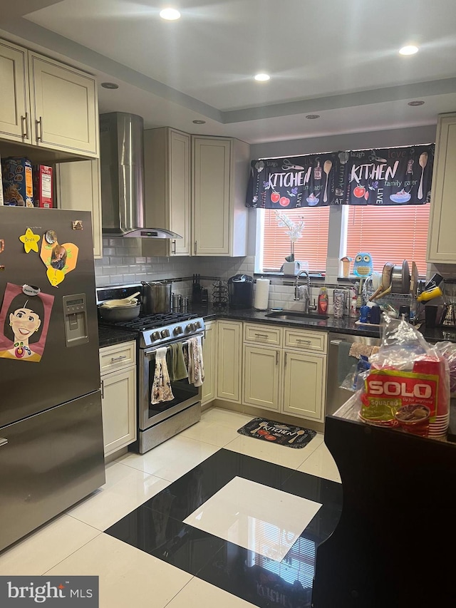 kitchen with a sink, backsplash, stainless steel appliances, wall chimney exhaust hood, and light tile patterned floors