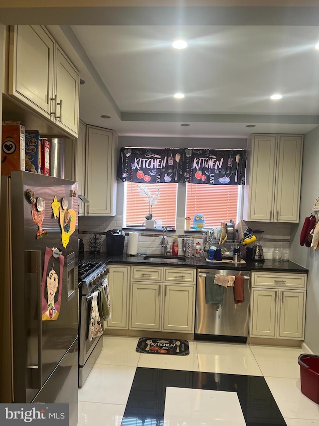 kitchen featuring dark countertops, backsplash, light tile patterned floors, stainless steel appliances, and a sink