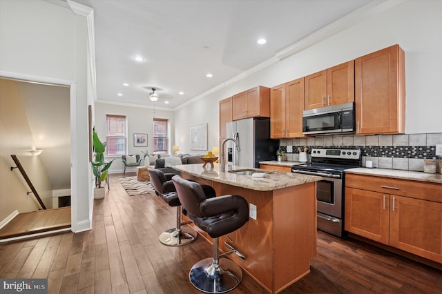 kitchen featuring a kitchen island with sink, tasteful backsplash, appliances with stainless steel finishes, and dark wood-style floors