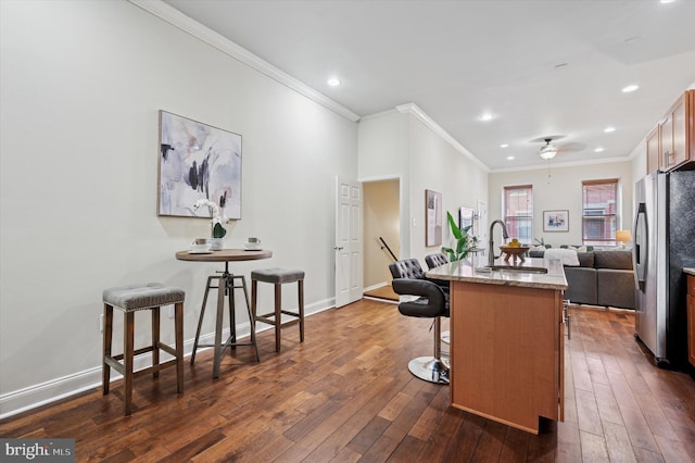 kitchen with a kitchen breakfast bar, open floor plan, freestanding refrigerator, baseboards, and dark wood-style flooring