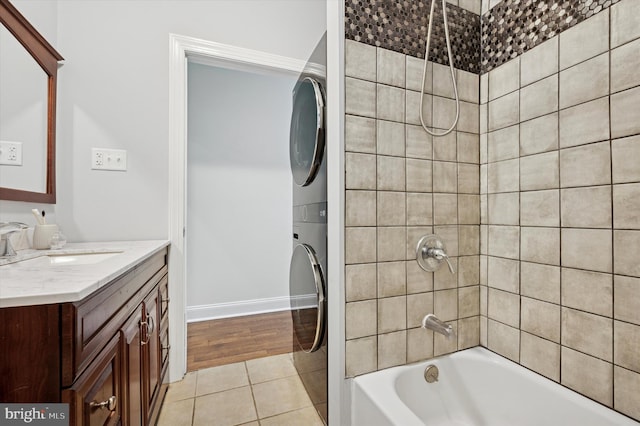 full bath with baseboards, stacked washer and clothes dryer, bathing tub / shower combination, tile patterned floors, and vanity