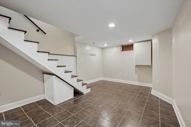 finished basement with recessed lighting, baseboards, dark tile patterned flooring, and stairs