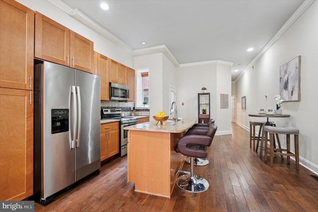 kitchen featuring a kitchen bar, a kitchen island with sink, dark wood-style floors, appliances with stainless steel finishes, and decorative backsplash