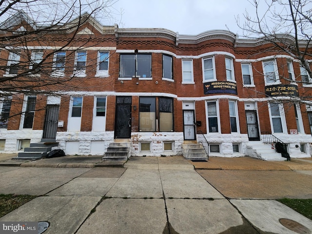 townhome / multi-family property featuring entry steps and brick siding