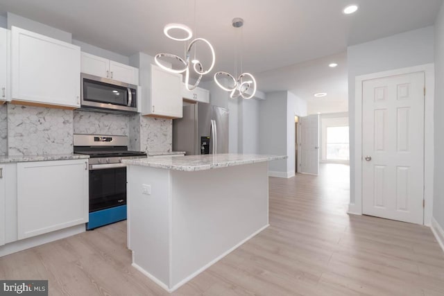 kitchen featuring tasteful backsplash, a kitchen island, white cabinetry, appliances with stainless steel finishes, and light wood finished floors