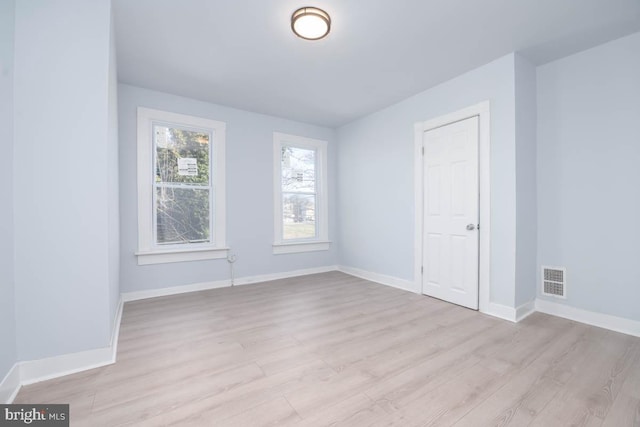 empty room featuring visible vents, baseboards, and light wood finished floors