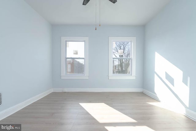 unfurnished room featuring plenty of natural light, baseboards, and light wood-type flooring