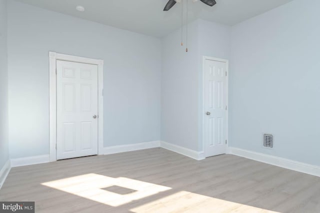 empty room with baseboards, light wood-type flooring, and ceiling fan