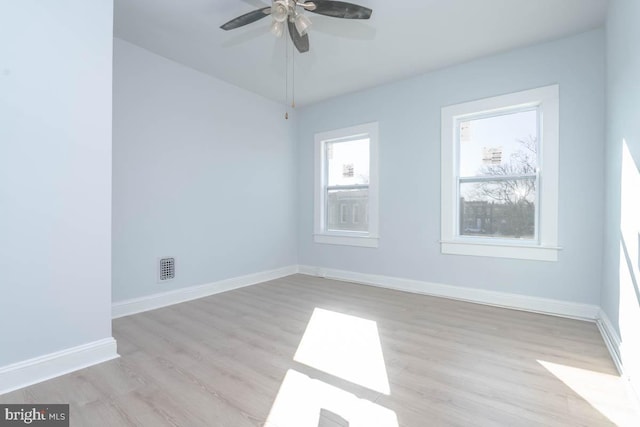 empty room with visible vents, baseboards, light wood finished floors, and ceiling fan