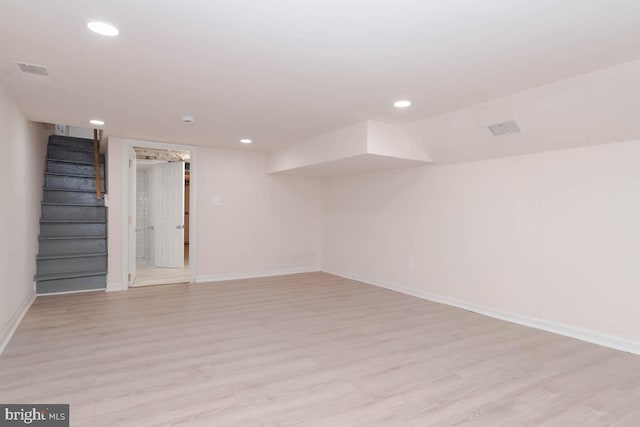 finished basement with light wood finished floors, visible vents, baseboards, stairs, and recessed lighting