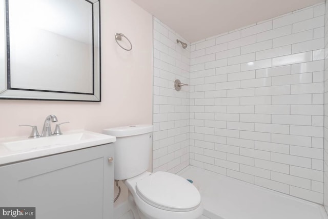 full bathroom featuring tiled shower, toilet, and vanity