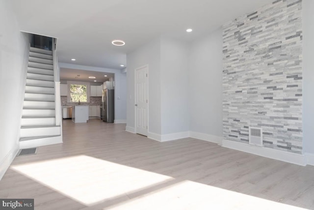 interior space featuring visible vents, stairway, light wood-type flooring, and baseboards