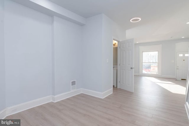 empty room featuring visible vents, baseboards, and light wood finished floors