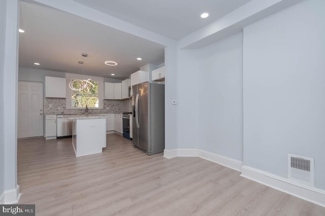 kitchen with visible vents, stainless steel appliances, light wood-style floors, light countertops, and decorative backsplash