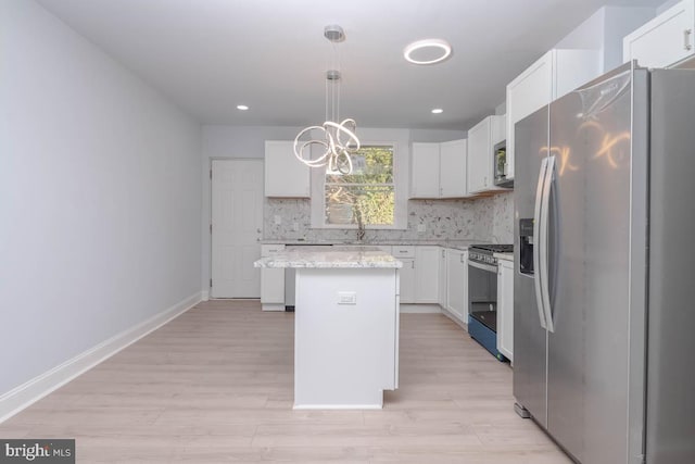 kitchen featuring a sink, a kitchen island, backsplash, white cabinetry, and stainless steel appliances