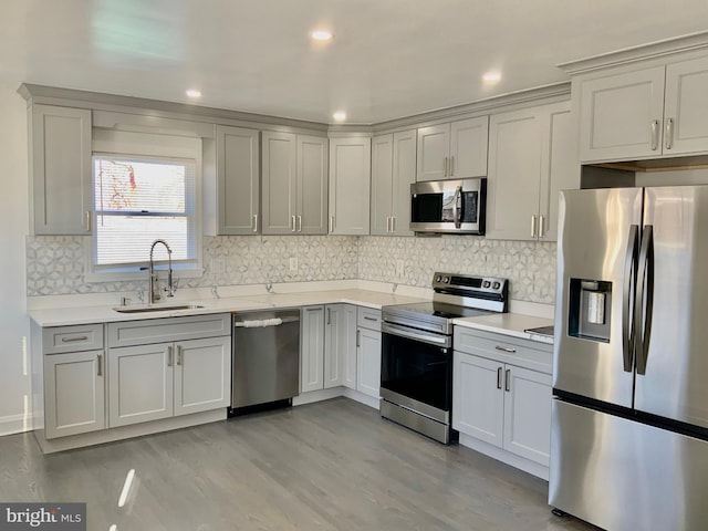 kitchen featuring light wood-type flooring, stainless steel appliances, light countertops, and a sink