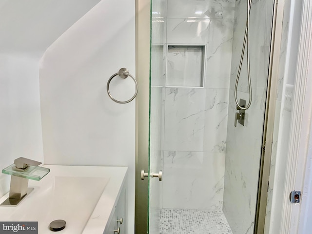 bathroom featuring a marble finish shower and vanity