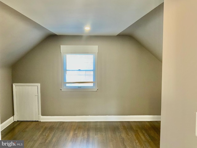 additional living space featuring baseboards, wood finished floors, and vaulted ceiling