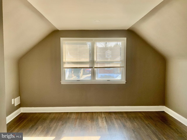 additional living space featuring visible vents, baseboards, dark wood-type flooring, and lofted ceiling