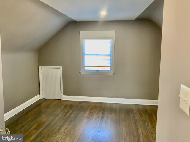 additional living space with baseboards, wood finished floors, and vaulted ceiling