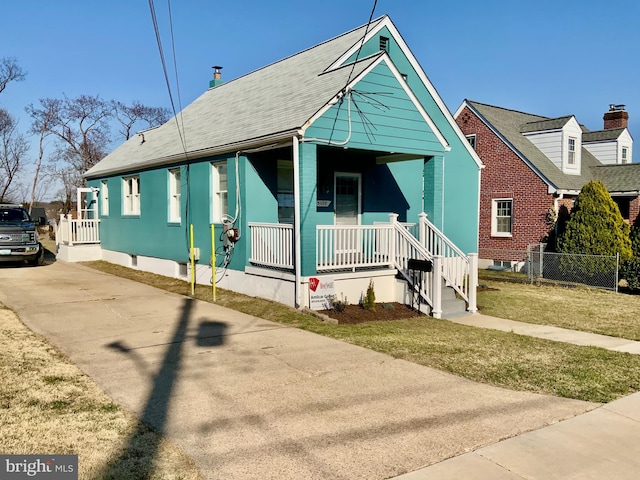 bungalow with a porch, fence, a front lawn, and driveway