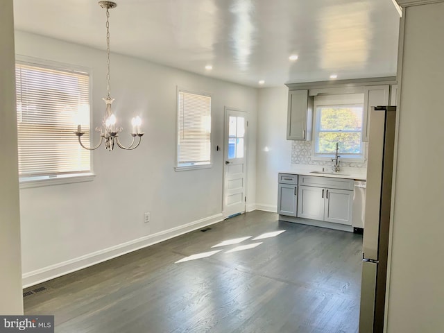 kitchen with backsplash, baseboards, gray cabinets, an inviting chandelier, and a sink