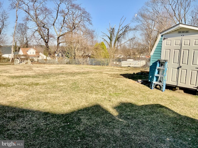 view of yard featuring an outbuilding, fence, and a shed