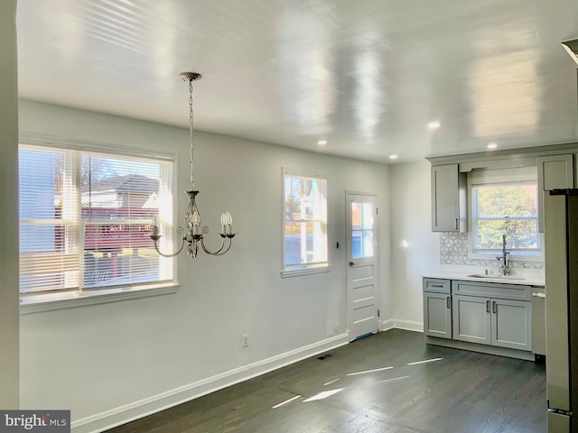 kitchen featuring a notable chandelier, gray cabinets, backsplash, and a sink