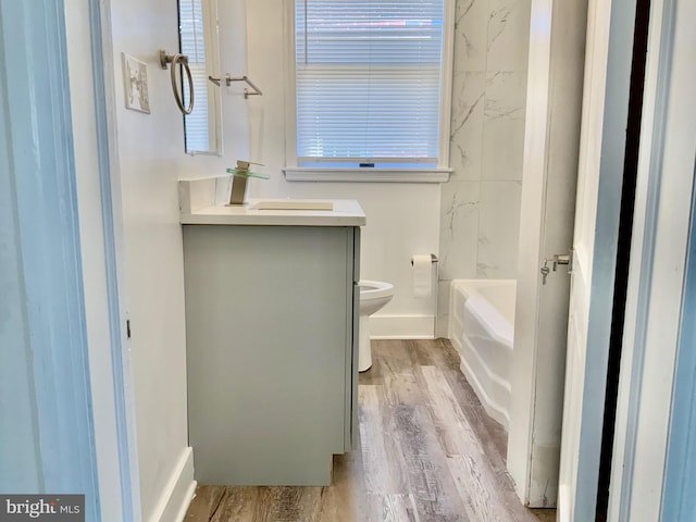 full bathroom with toilet, wood finished floors, vanity, and a bath