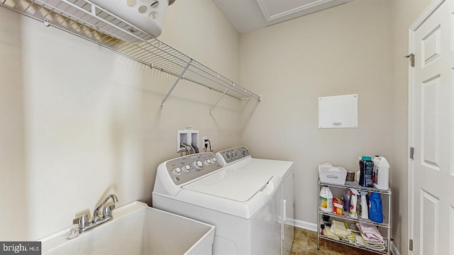 clothes washing area featuring laundry area, washer and dryer, baseboards, and a sink