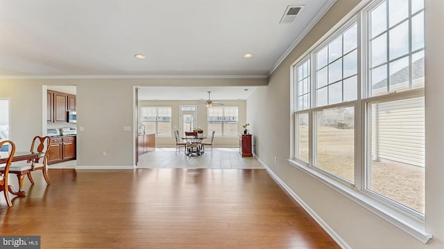 dining space with ornamental molding, wood finished floors, visible vents, and baseboards