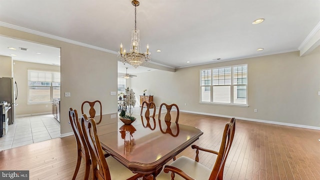 dining area featuring light wood-style flooring, ornamental molding, ceiling fan with notable chandelier, recessed lighting, and baseboards