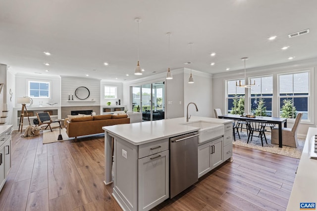 kitchen with dark wood finished floors, a sink, crown molding, and stainless steel dishwasher