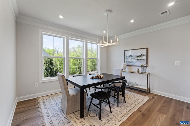 dining area with baseboards, wood finished floors, an inviting chandelier, and ornamental molding