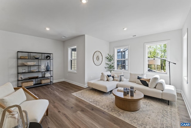 living room with recessed lighting, visible vents, baseboards, and wood finished floors