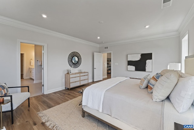 bedroom featuring visible vents, crown molding, baseboards, and wood finished floors