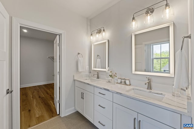 bathroom with double vanity, wood finished floors, baseboards, and a sink