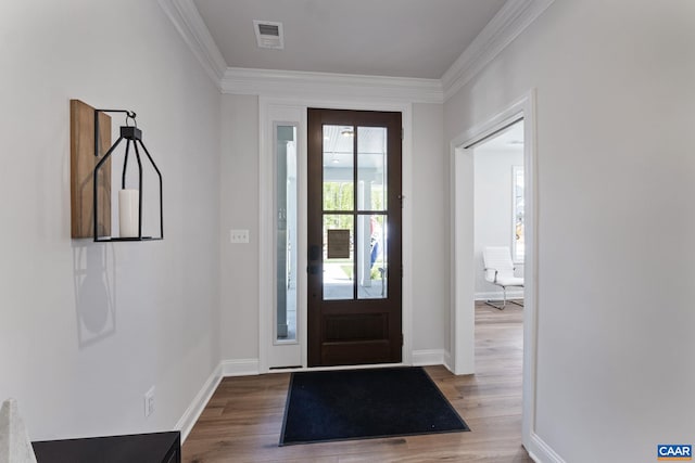 entrance foyer featuring baseboards, wood finished floors, visible vents, and ornamental molding