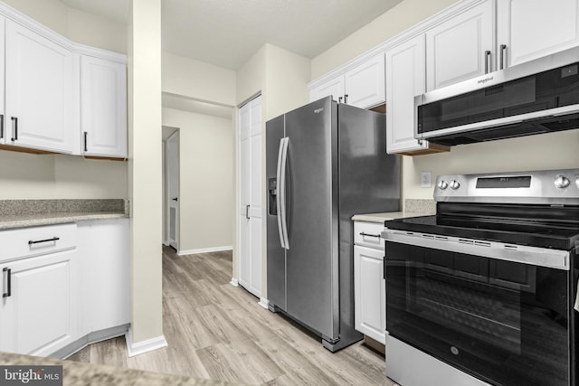 kitchen with baseboards, stainless steel appliances, light countertops, white cabinets, and light wood-style floors