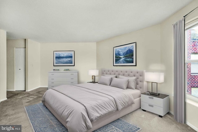 bedroom with light colored carpet and baseboards