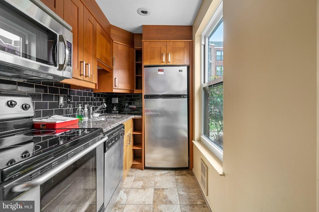 kitchen with stone counters, stainless steel appliances, a healthy amount of sunlight, and decorative backsplash