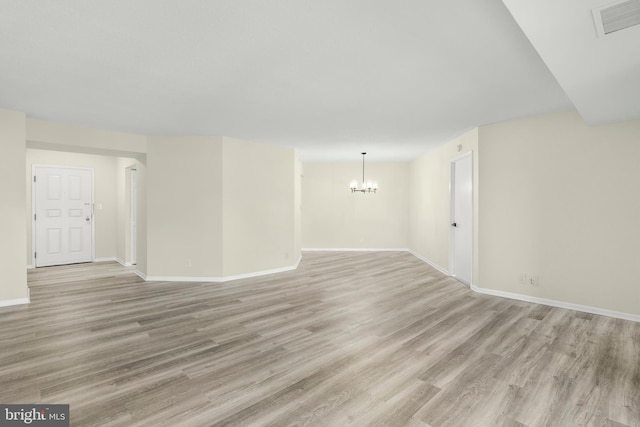 empty room with light wood-type flooring, baseboards, visible vents, and a chandelier