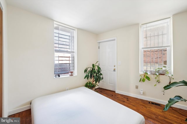 bedroom with visible vents, baseboards, and wood finished floors