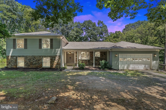 tri-level home featuring stone siding, driveway, an attached garage, and a shingled roof