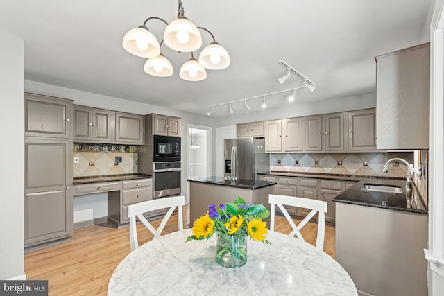 kitchen featuring dark stone counters, light wood-style flooring, gray cabinetry, stainless steel appliances, and a sink